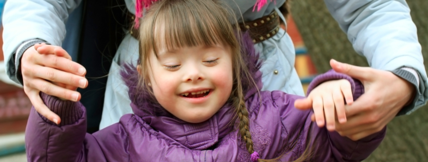 Das Foto zeigt ein fröhlich lächelndes Kind mit Behinderung