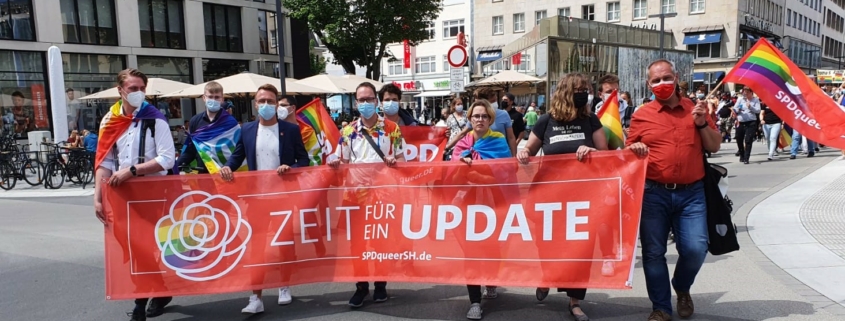 Mathias Stein läuft auf einer Demonstration für LGBTIQ mit und hält mit anderen Sozialdemokrat:innen gemeinsam ein Banner mit der Aufschrift "Zeit für ein Update" und einer Regenbogen Rose